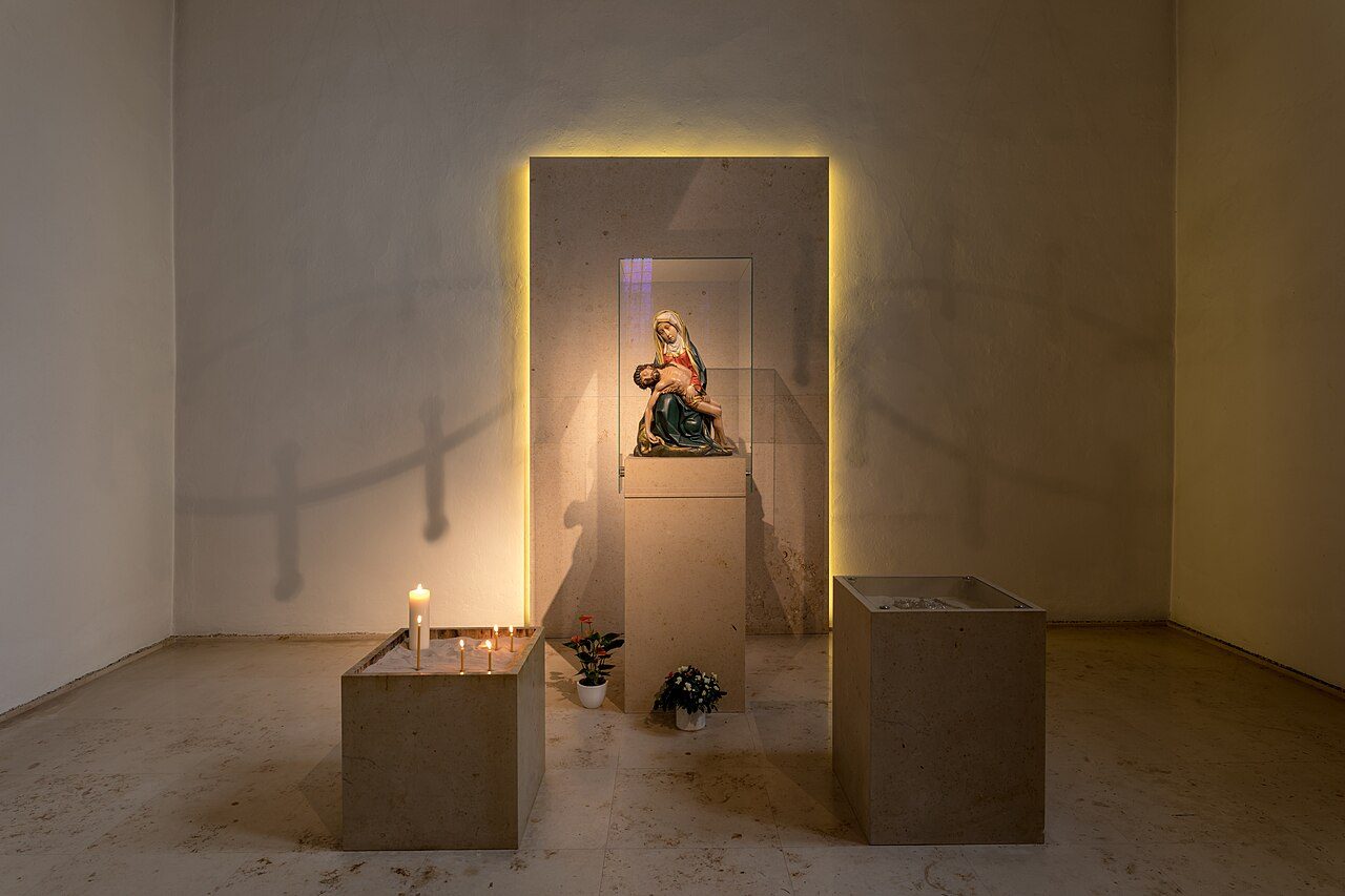 Votive candles burning on a stand in a quiet chapel