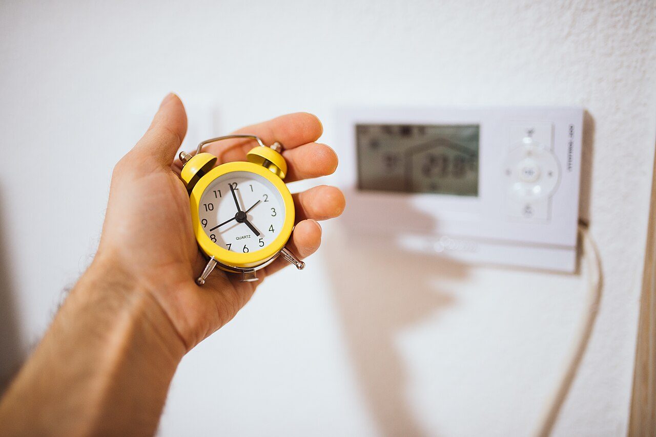 A vintage yellow alarm clock, held in the hand