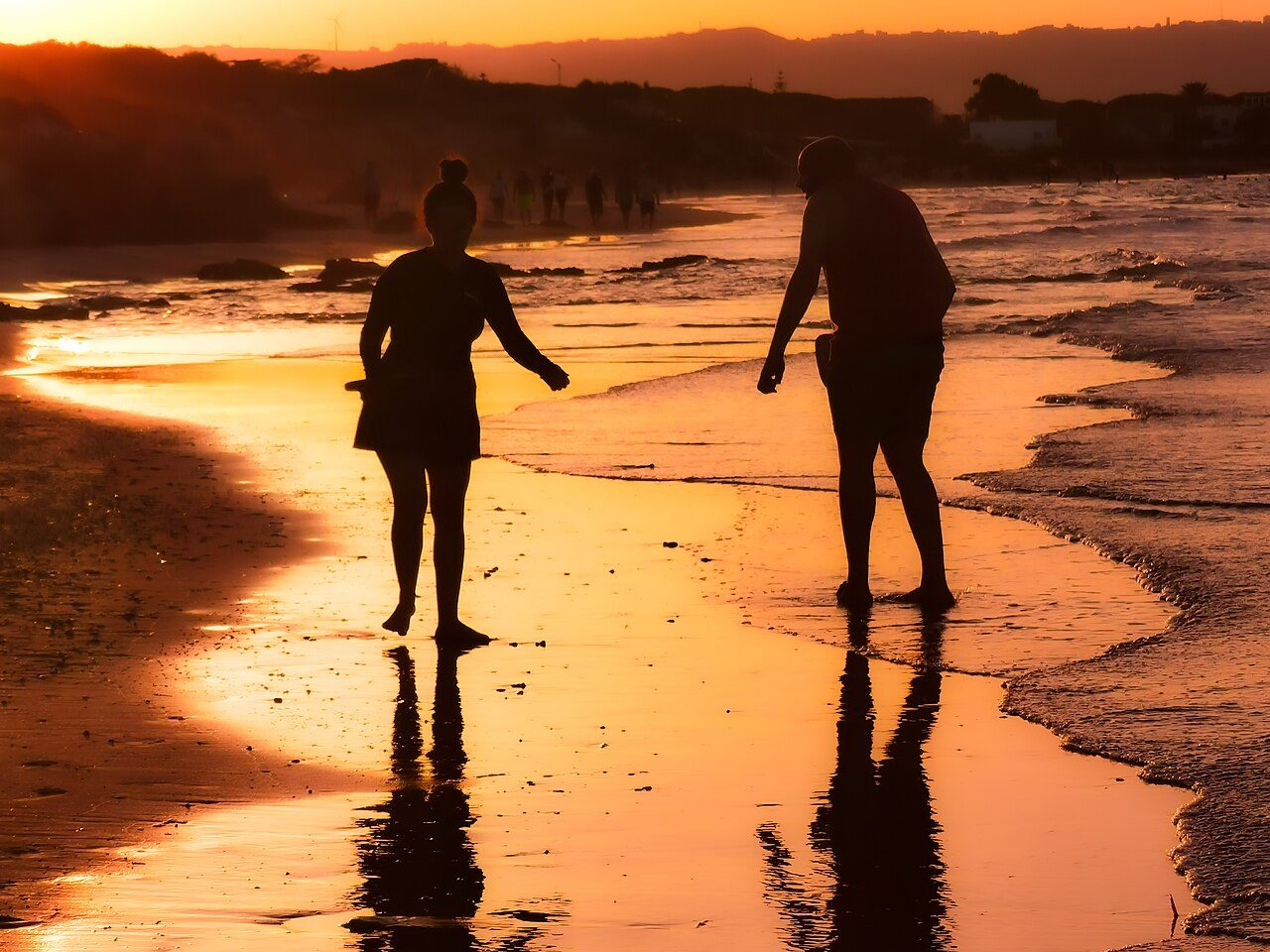 A couple silhouetted on the shore at golden sunset